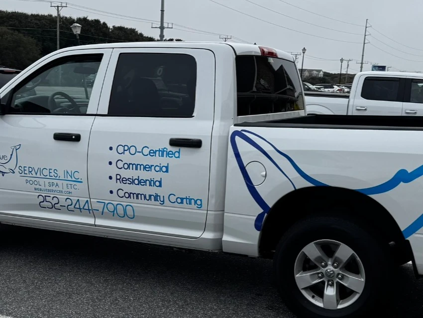 A Big Blue Services truck with the company whale mark and phone number on the door