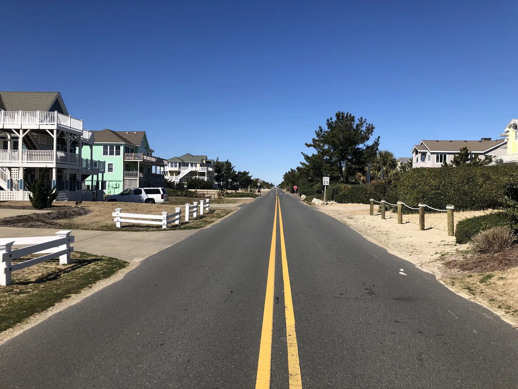 A clear residential roadway and curb beside neighborhood homes.