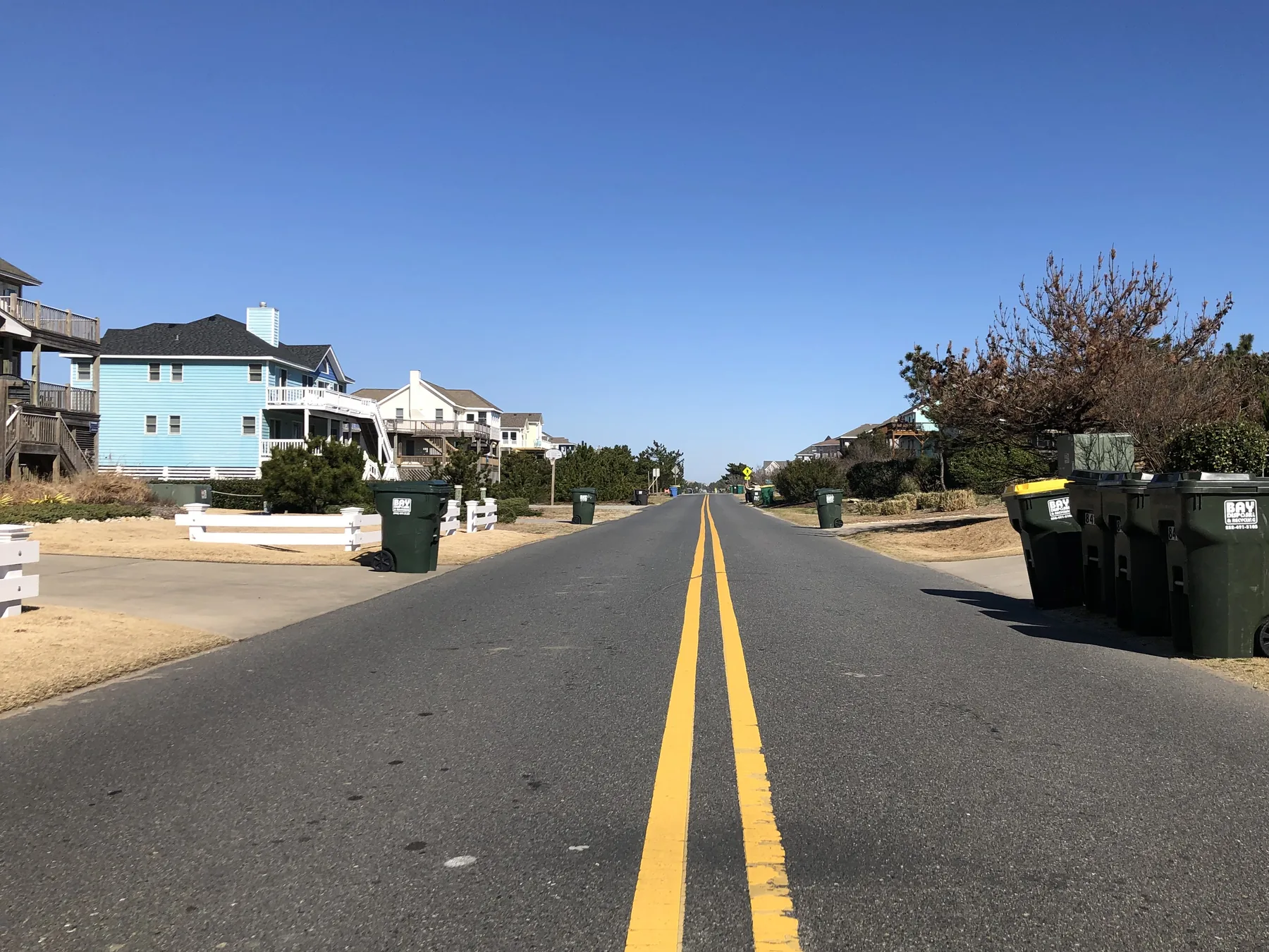 Several green carts lined along a residential street.