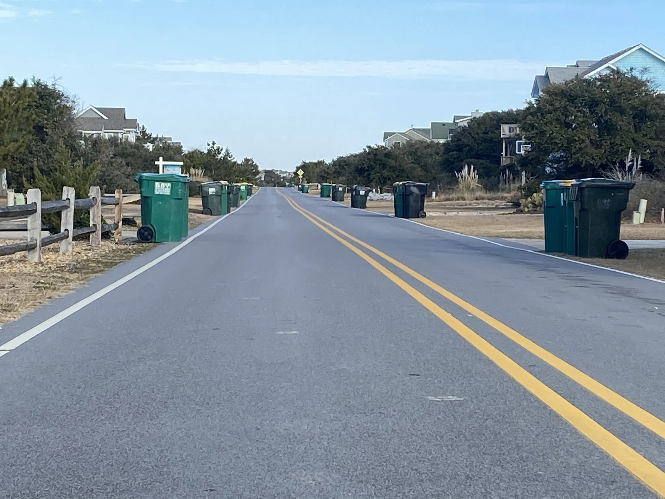 Trash and recycling carts lined along a residential community street.